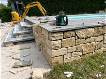 JPM Construction | Réalisation : Terrasse à Jodoigne avec chape, carrelage en pierre naturelle égyptienne, escalier pour jolie piscine et parement pierre naturelle 3